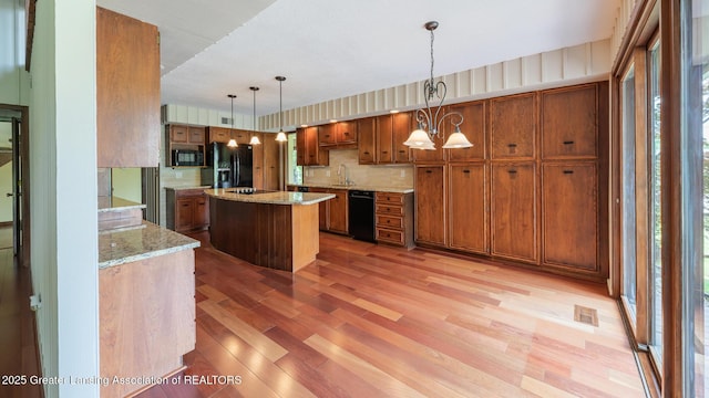 280 Winterberry Ln, Okemos, MI 48864 - kitchen with black appliances, brown cabinetry, light wood finished floors, and a kitchen island