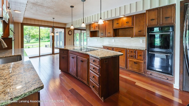 280 Winterberry Ln, Okemos, MI 48864 - kitchen featuring black appliances, dark wood-style floors, backsplash, a center island, and a textured ceiling