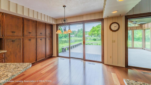 280 Winterberry Ln, Okemos, MI 48864 - unfurnished dining area featuring light wood-style flooring, a textured ceiling, and wooden walls