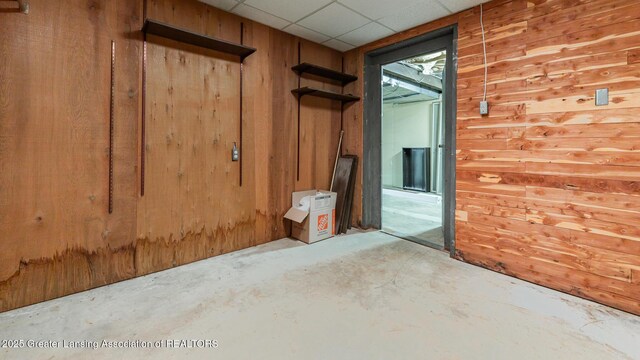 280 Winterberry Ln, Okemos, MI 48864 - empty room with unfinished concrete floors, wood walls, and a paneled ceiling