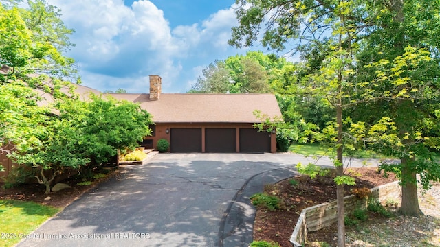 280 Winterberry Ln, Okemos, MI 48864 - view of front of house with asphalt driveway, a chimney, and a garage