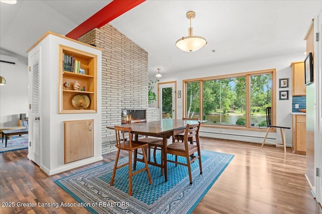 10138 Baron Blvd, Dimondale, MI 48821 - dining space featuring baseboard heating, a brick fireplace, wood finished floors, and a wall mounted AC