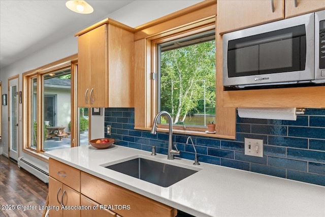 10138 Baron Blvd, Dimondale, MI 48821 - kitchen with stainless steel microwave, a baseboard heating unit, tasteful backsplash, light countertops, and dark wood-style flooring