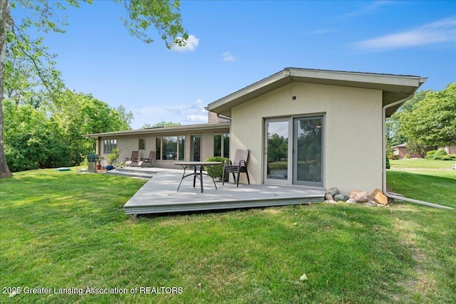 10138 Baron Blvd, Dimondale, MI 48821 - rear view of house featuring stucco siding, a wooden deck, and a yard
