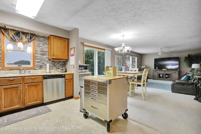 14235 Saxton Rd, Springport, MI 49284 - kitchen with stainless steel dishwasher, light colored carpet, a chandelier, brown cabinets, and a textured ceiling