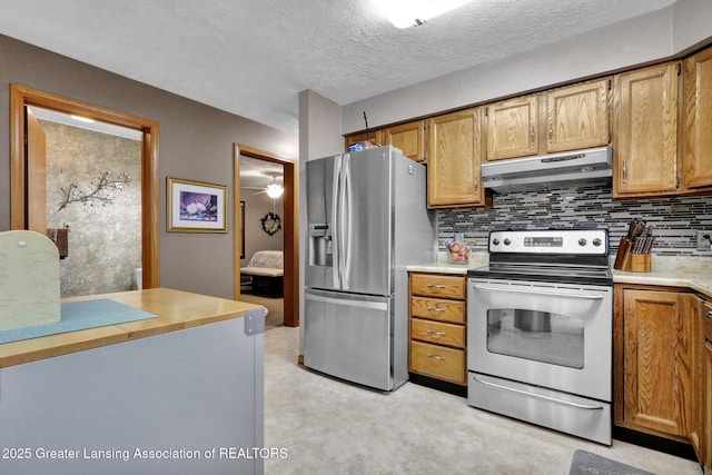 14235 Saxton Rd, Springport, MI 49284 - kitchen featuring stainless steel appliances, under cabinet range hood, decorative backsplash, light countertops, and brown cabinets