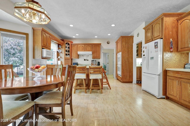 1823 Cricket Ln, East Lansing, MI 48823 - kitchen featuring white appliances, light wood-style floors, recessed lighting, brown cabinetry, and a chandelier