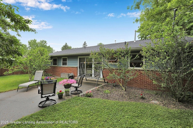 528 Thomas L Pkwy, Lansing, MI 48917 - back of property with brick siding, a patio, a lawn, and a shingled roof