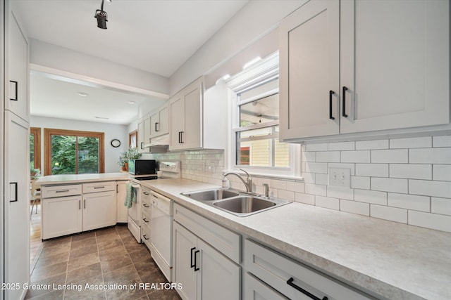 2391 Shawnee Trl, Okemos, MI 48864 - kitchen with white dishwasher, a peninsula, light countertops, stove, and backsplash