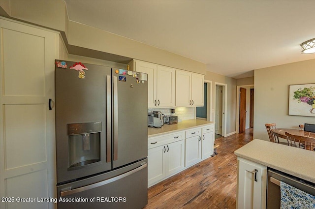 2300 Hampshire Rd, Lansing, MI 48911 - kitchen with stainless steel appliances, white cabinets, light wood finished floors, light countertops, and tasteful backsplash