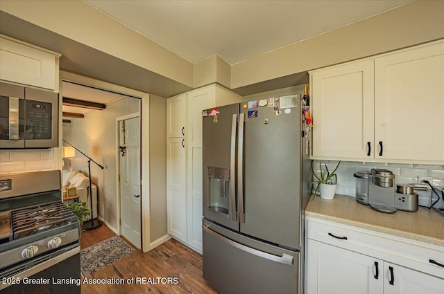 2300 Hampshire Rd, Lansing, MI 48911 - kitchen with stainless steel appliances, light countertops, backsplash, and dark wood finished floors