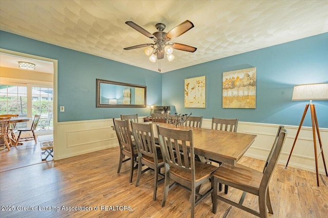 2300 Hampshire Rd, Lansing, MI 48911 - dining area with wainscoting, wood finished floors, a ceiling fan, and a decorative wall