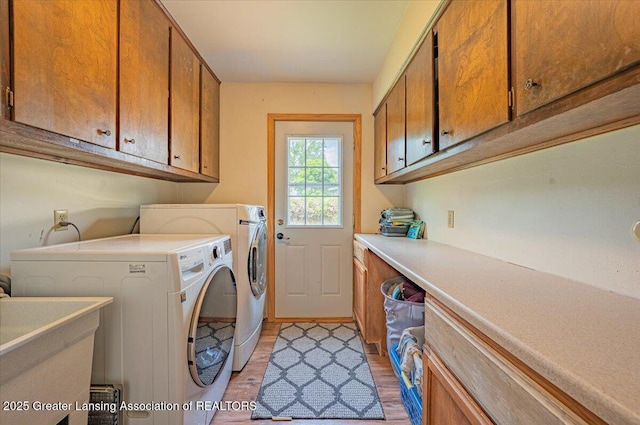 2300 Hampshire Rd, Lansing, MI 48911 - laundry area with cabinet space, washer and dryer, and light wood-type flooring