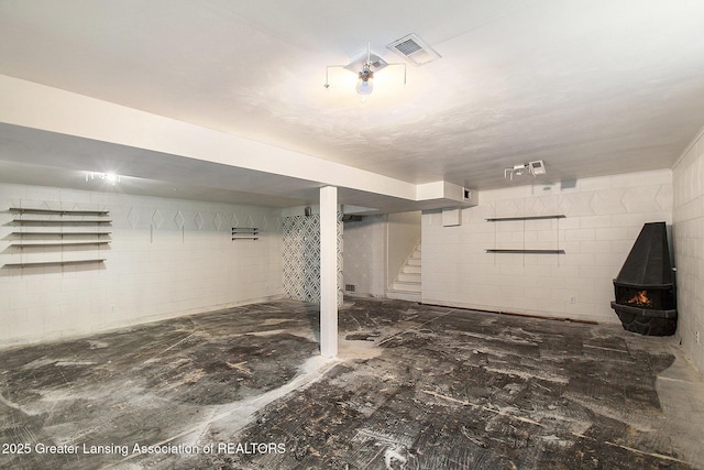 3739 Ridgefield Rd, Lansing, MI 48906 - finished basement featuring stairs, concrete block wall, and a wood stove