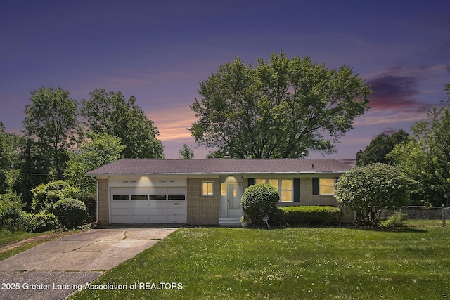 3739 Ridgefield Rd, Lansing, MI 48906 - view of front of home with brick siding, a garage, a lawn, and concrete driveway