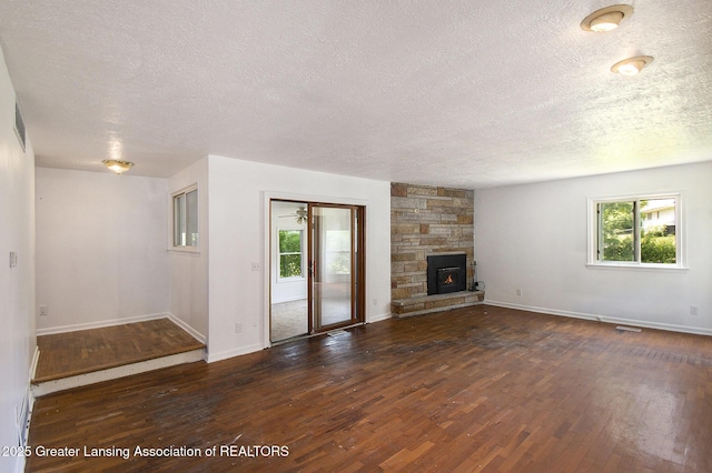 3739 Ridgefield Rd, Lansing, MI 48906 - unfurnished living room featuring a textured ceiling, wood finished floors, and a stone fireplace