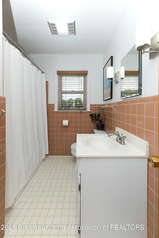943 Lantern Hill Dr, East Lansing, MI 48823 - bathroom featuring tile walls, tile patterned floors, vanity, a wainscoted wall, and curtained shower