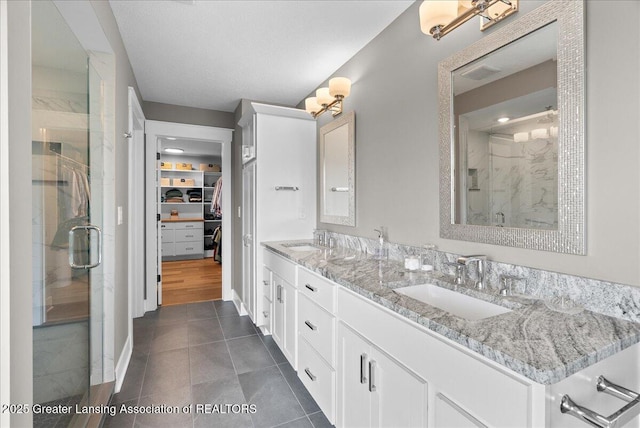 6102 Sleepy Hollow Ln, East Lansing, MI 48823 - bathroom with a stall shower, double vanity, a spacious closet, and tile patterned floors