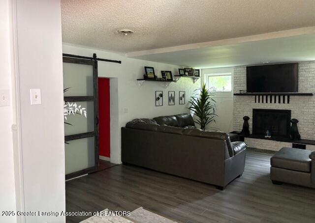6321 Marywood Ave, Lansing, MI 48911 - living area with a barn door, wood finished floors, a fireplace, and a textured ceiling