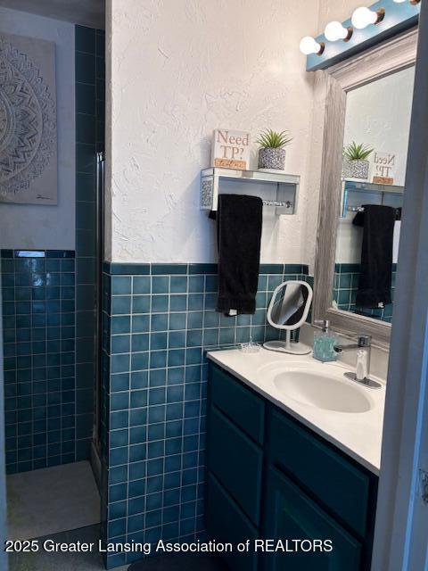 6321 Marywood Ave, Lansing, MI 48911 - bathroom featuring vanity, a wainscoted wall, tile walls, and tiled shower
