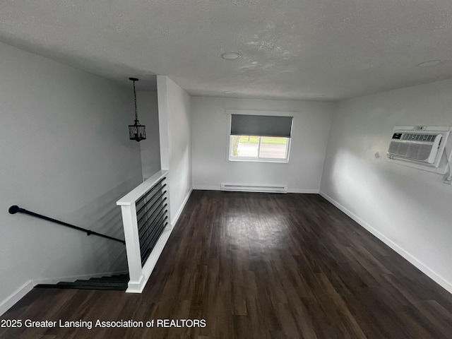4733 S Pennsylvania Ave, Lansing, MI 48910 - spare room featuring a baseboard radiator, dark wood finished floors, a textured ceiling, a wall unit AC, and a chandelier