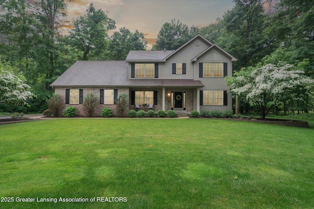 3901 W Howe Rd, Dewitt, MI 48820 - traditional home featuring a front yard, covered porch, brick siding, and roof with shingles