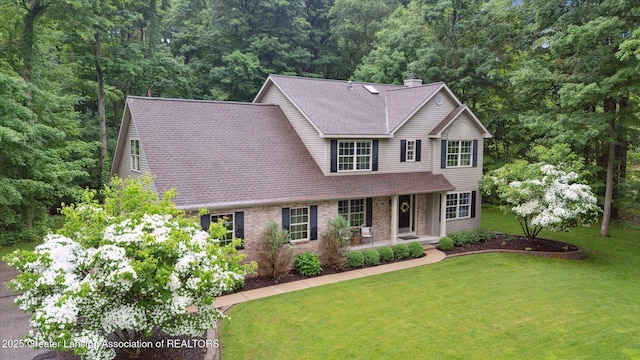 3901 W Howe Rd, Dewitt, MI 48820 - view of front of house featuring a shingled roof, a front lawn, a chimney, brick siding, and a wooded view