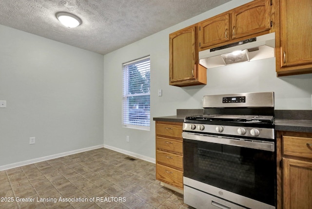 1015 Lake Lansing Rd, Lansing, MI 48906 - kitchen with under cabinet range hood, stainless steel gas range oven, dark countertops, a textured ceiling, and brown cabinets