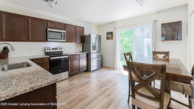 1118 River Oaks Dr, Dewitt, MI 48820 - kitchen featuring stainless steel appliances, decorative backsplash, light wood finished floors, and light stone countertops