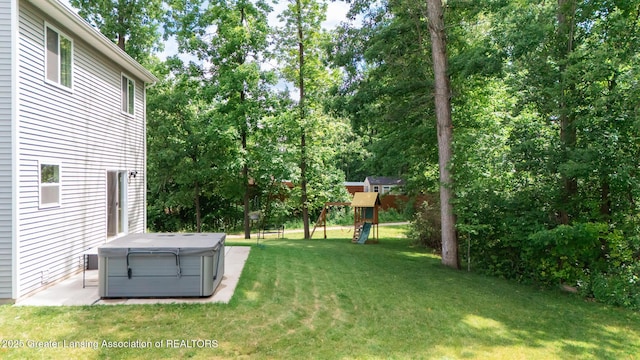 1118 River Oaks Dr, Dewitt, MI 48820 - view of green lawn featuring a hot tub, a playground, and view of scattered trees