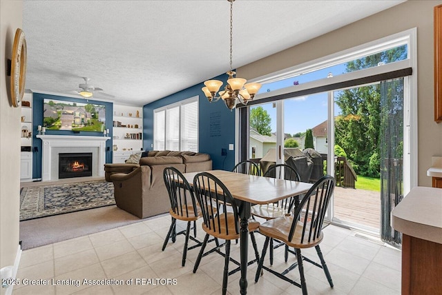 10889 Pointe W Blvd, Grand Ledge, MI 48837 - dining area with a chandelier, a lit fireplace, a ceiling fan, a textured ceiling, and built in features