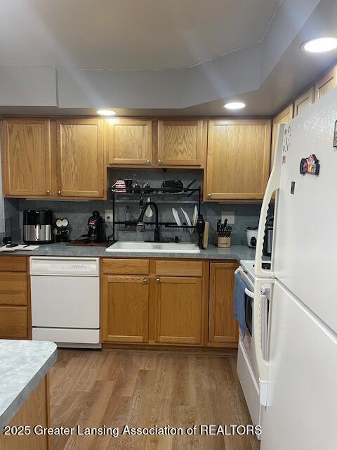 5535 W St Joe Hwy Unit B12, Lansing, MI 48917 - kitchen with white appliances, decorative backsplash, light wood-style floors, and light countertops