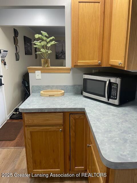 5535 W St Joe Hwy Unit B12, Lansing, MI 48917 - kitchen with stainless steel microwave, light countertops, and brown cabinetry