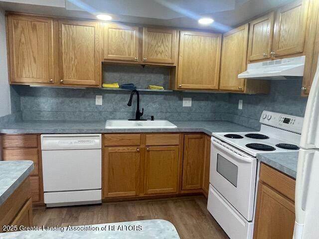 5535 W St Joe Hwy Unit B12, Lansing, MI 48917 - kitchen featuring white appliances, under cabinet range hood, wood finished floors, and decorative backsplash