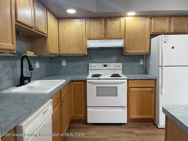 5535 W St Joe Hwy Unit B12, Lansing, MI 48917 - kitchen featuring white appliances, under cabinet range hood, tasteful backsplash, and light wood finished floors