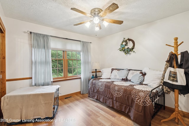 888 S Waverly Rd, Eaton Rapids, MI 48827 - bedroom featuring wood finished floors, a textured ceiling, and a ceiling fan