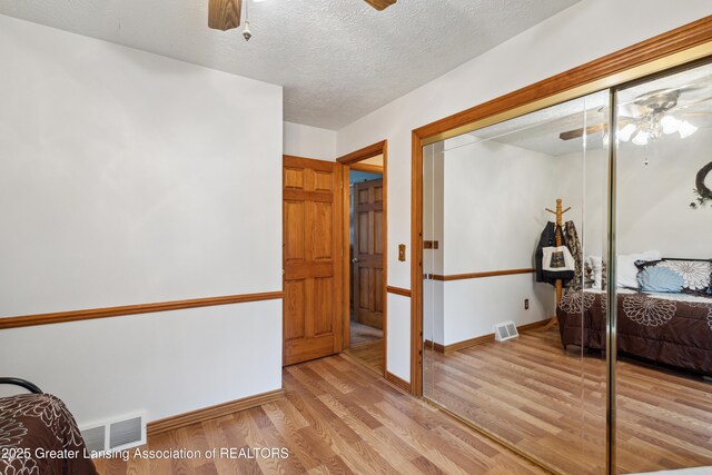 888 S Waverly Rd, Eaton Rapids, MI 48827 - bedroom featuring wood finished floors, a closet, a textured ceiling, and a ceiling fan