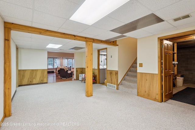 888 S Waverly Rd, Eaton Rapids, MI 48827 - basement featuring wainscoting, a drop ceiling, wood walls, stairway, and carpet flooring