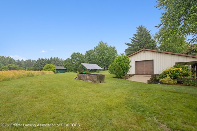 888 S Waverly Rd, Eaton Rapids, MI 48827 - view of grassy yard with an outdoor structure, a detached garage, and driveway