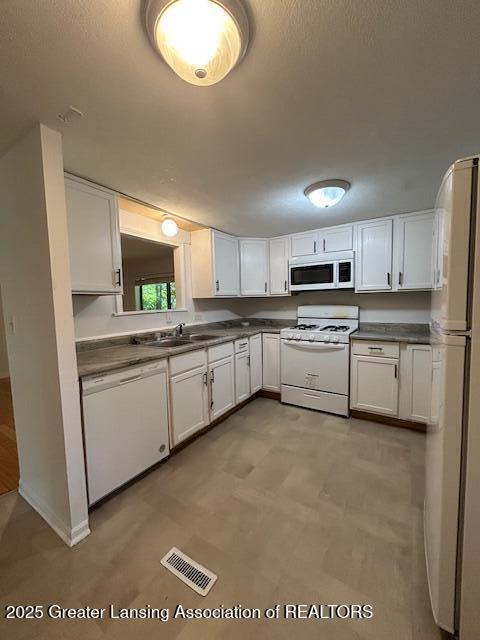 1318 Massachusetts Ave, Lansing, MI 48906 - kitchen with white appliances, white cabinets, and dark countertops