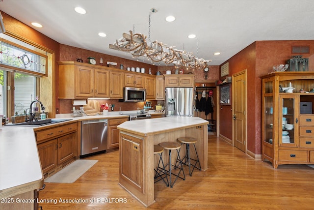 502 W Spring Meadows Ln, Dewitt, MI 48820 - kitchen with stainless steel appliances, a center island, light wood finished floors, light countertops, and a kitchen breakfast bar
