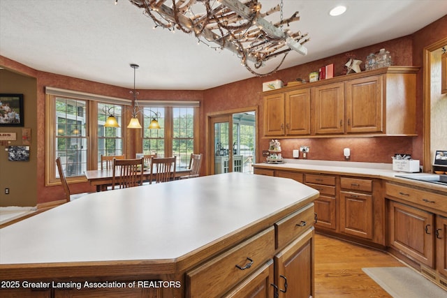 502 W Spring Meadows Ln, Dewitt, MI 48820 - kitchen with a chandelier, brown cabinets, light countertops, a kitchen island, and hanging light fixtures