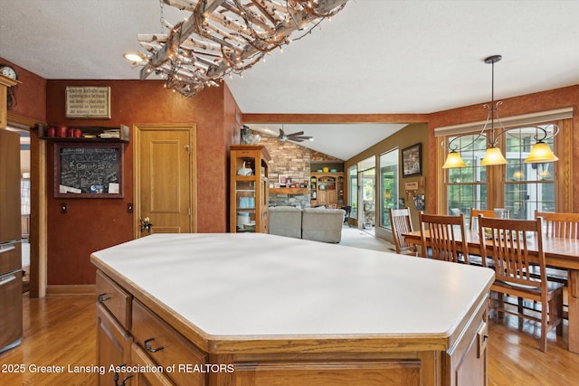 502 W Spring Meadows Ln, Dewitt, MI 48820 - kitchen featuring light wood-style floors, a ceiling fan, a center island, and brown cabinets