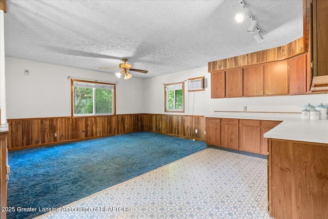 952 Leslie St, Lansing, MI 48912 - unfurnished living room featuring wainscoting, rail lighting, ceiling fan, a textured ceiling, and wood walls