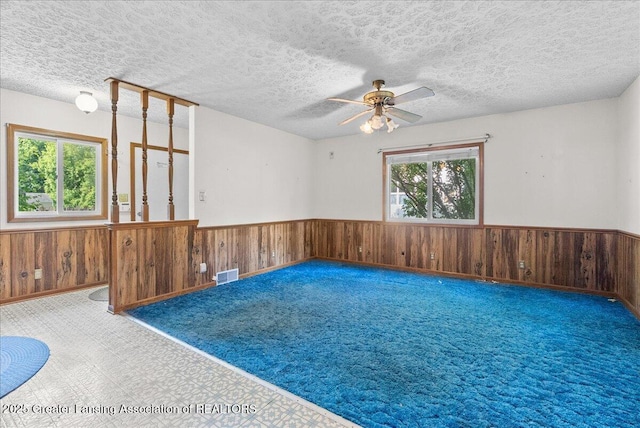 952 Leslie St, Lansing, MI 48912 - empty room featuring a wainscoted wall, a ceiling fan, wood walls, a textured ceiling, and carpet