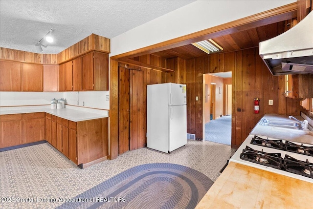 952 Leslie St, Lansing, MI 48912 - kitchen featuring white appliances, under cabinet range hood, wood walls, brown cabinets, and a textured ceiling