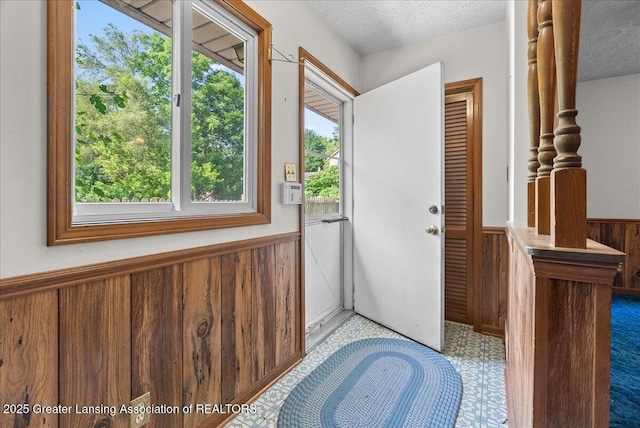 952 Leslie St, Lansing, MI 48912 - doorway to outside featuring a wainscoted wall, a textured ceiling, wood walls, and tile patterned floors