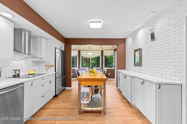 1122 Farwood Dr, East Lansing, MI 48823 - kitchen featuring appliances with stainless steel finishes, light countertops, backsplash, white cabinets, and light wood-type flooring