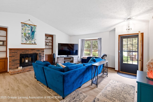 2440 Sower Blvd, Okemos, MI 48864 - living room with vaulted ceiling, light wood finished floors, a brick fireplace, built in shelves, and a textured ceiling