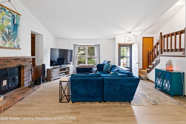 2440 Sower Blvd, Okemos, MI 48864 - living room with lofted ceiling, wood finished floors, a fireplace, stairway, and a textured ceiling